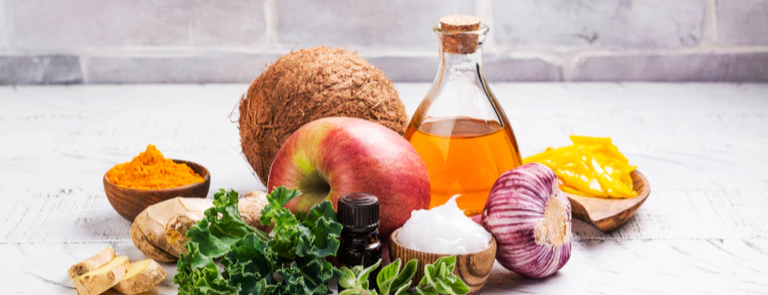 apple, coconut, onion, and other herbs and vegetables with a bottle of cooking oil